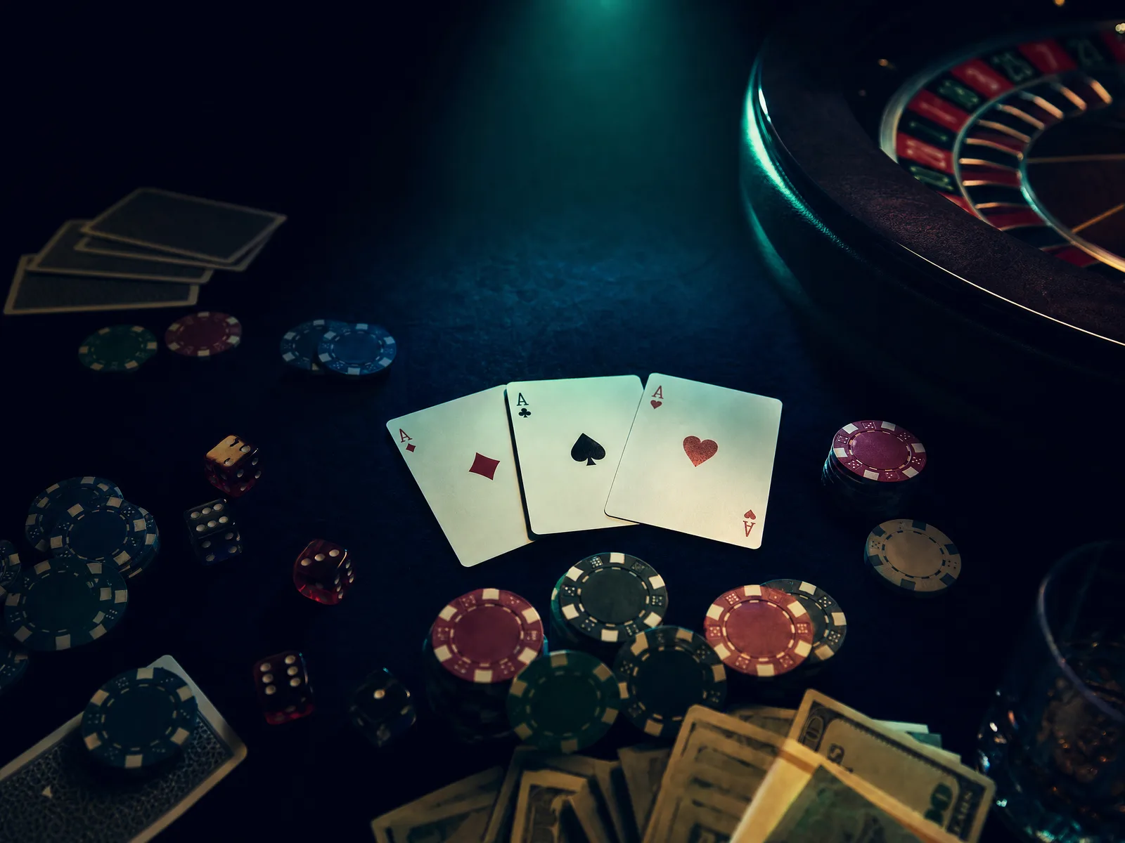 Premium casino games table with cards chips and roulette wheel under dramatic spotlight